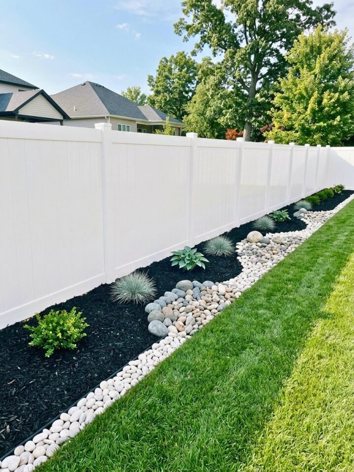 mulch and stone fence line landscaping idea